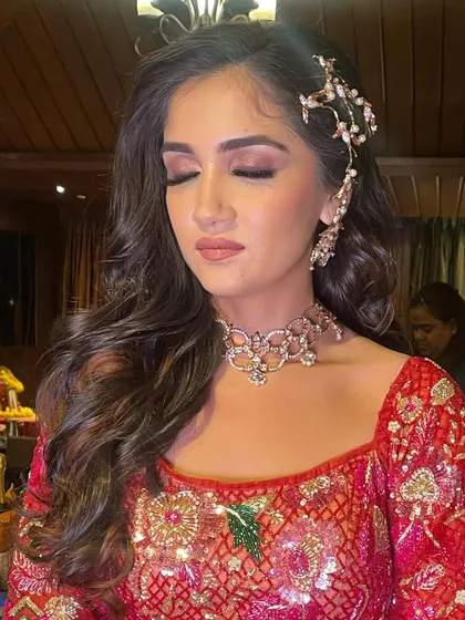 A glamorous sangeet look with soft, flowing waves and a beautiful, intricate hair accessory on one side.