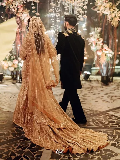 The couple walking away, showing the stunning back of the groom's sherwani and the bride's flowing train. A perfect exit.