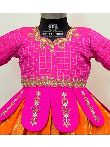 This close-up shows the unique details of a pink blouse, including a grid pattern, mirror work, and an embroidered petal-style peplum.