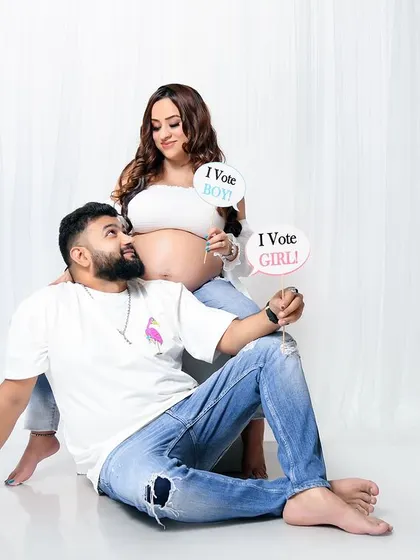 A fun and playful shot from a casual maternity session. The couple uses "I vote boy" and "I vote girl" props for a cute gender reveal guessing game.