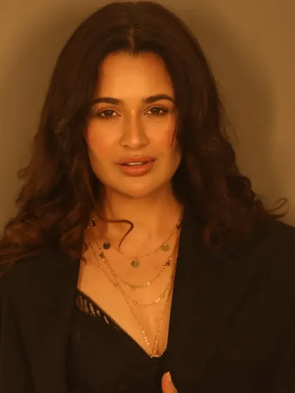 A warm, glowing portrait. The lighting enhances the radiant finish of the makeup, giving her skin an ethereal quality.