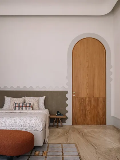 The guest bedroom at Rehethaan is a tiny oasis. A wavy, textured detail runs along the wall, and an arched niche filled with pottery adds a pop of color and character.