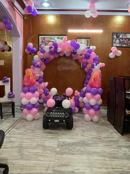 A fun addition to the princess-themed party, a small toy jeep is parked in front of the balloon arch, ready for the birthday girl.