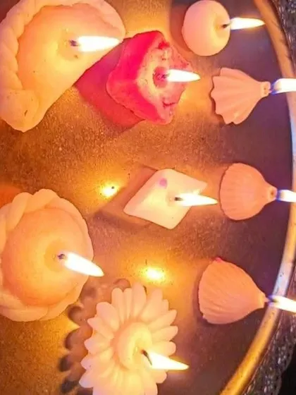 A lit display of various mithai candles, including Gujiya and Modak shapes, floating in a decorative bowl. This is a great way to showcase your finished products for festive decor.