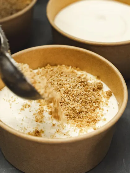A dusting of biscuit crumble is added to a layer of cream, a key component in our Banoffee Pie.