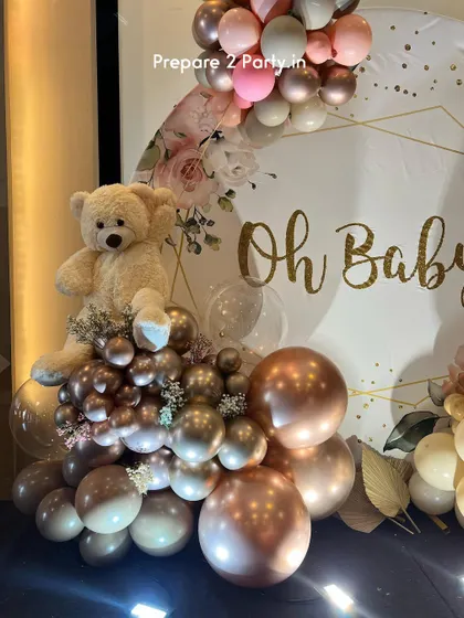 A detail shot of the "Oh Baby" setup, focusing on the plush teddy bear sitting amongst a cluster of metallic and pastel balloons, adding a soft and cuddly element to the decor.