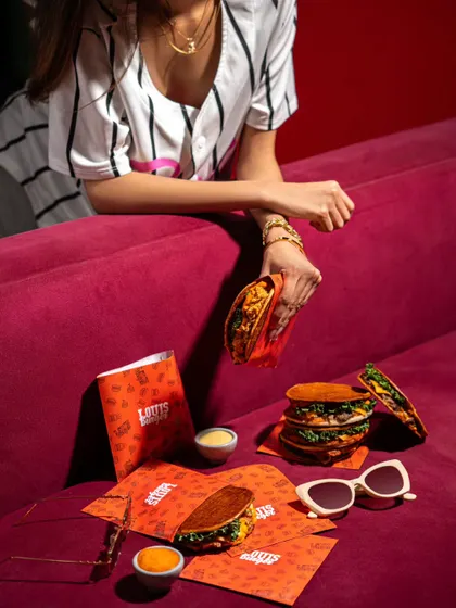 A lifestyle-oriented product shoot for Louis Burger's tacos. The setup with sunglasses and a model creates a cool, fashionable vibe for the brand.