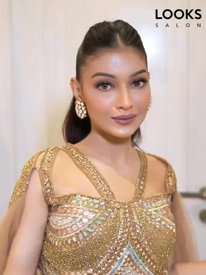 A close-up of a glamorous party makeup look. We focused on creating a flawless, radiant complexion and defined eyes to pair with this stunning, heavily embellished golden outfit.