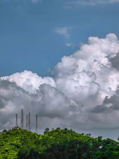 Even man-made structures can be part of a powerful landscape. The contrast between the green hill and the massive cloud formation creates a visually striking image.