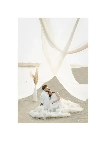 In love and ready for their miracle. The expecting mother rests her head on her partner's shoulder, a picture of peace and deep connection amidst a dreamy, sandy landscape.