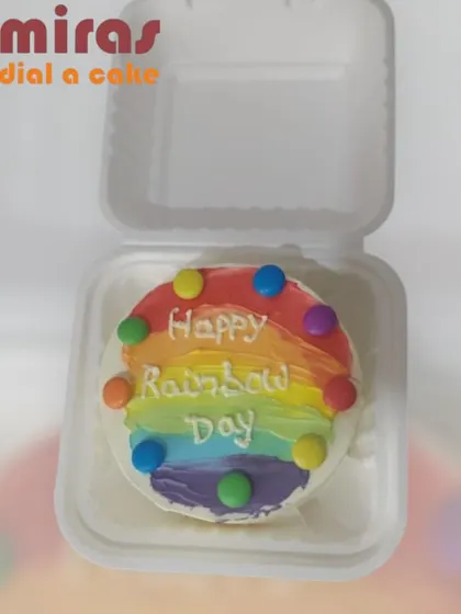 A bright and cheerful "Happy Rainbow Day" bento cake. This mini cake is decorated with a colorful rainbow frosting effect and topped with candy-coated chocolates for a simple and joyful treat.