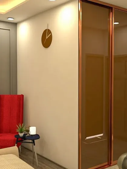 A bedroom featuring a wardrobe with bronze-tinted glass doors and a classic red accent chair. The wall paneling adds a touch of traditional elegance to the room.