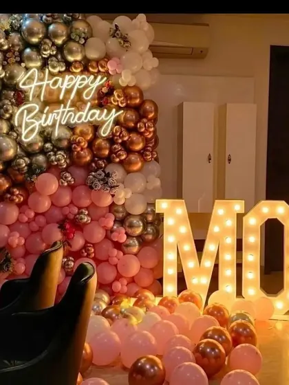 A "Happy Birthday Mom" celebration with a wall of pink, rose gold, and silver balloons and large "MOM" marquee letters.