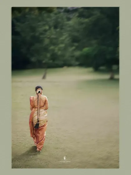 A shot of the bride from behind, walking across a vast green lawn, her traditional braided hair a beautiful focal point.