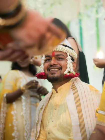 A joyful, candid portrait of the groom smiling as he is blessed during his Haldi ceremony.