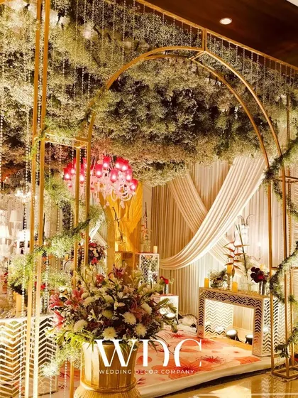 A grand entrance for a dream wedding, with golden arches, a ceiling of baby's breath, and lush floral arrangements, creating a truly opulent and magical feel.