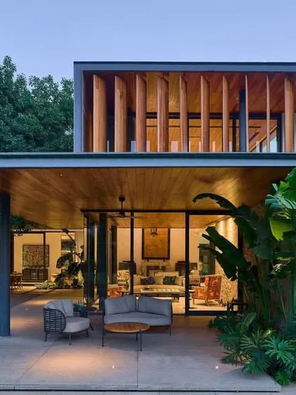 The combination of natural stone, warm wood, and vertical timber fins on the upper level gives the 'Patio House' a rich material palette that is both modern and earthy.