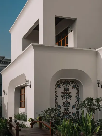 An exterior view showing our glass mosaic fresco set within the clean, arched architecture of a residential project. The artwork serves as a striking focal point, blending traditional craft with minimalist design.