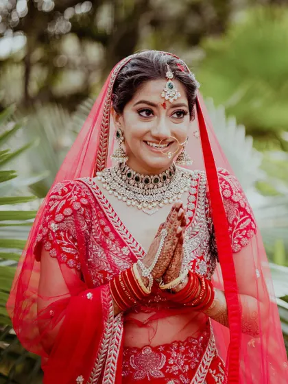 A radiant bride with her hands in a traditional 'namaste' pose, her smile welcoming the new chapter of her life.