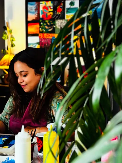 A candid shot of Sanchita painting, seen through the leaves of one of my studio plants. It captures the calm and natural atmosphere of the space.