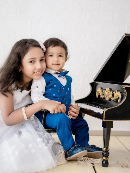 A charming photo of a brother and sister posing with a miniature piano prop. Using props can make the session more fun for kids and result in adorable photos.