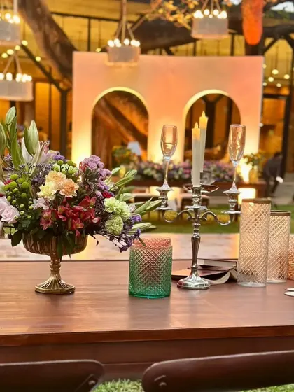 A close-up of the tablescape at the garden reception, featuring a mix of colorful flowers, candles, and elegant glassware.