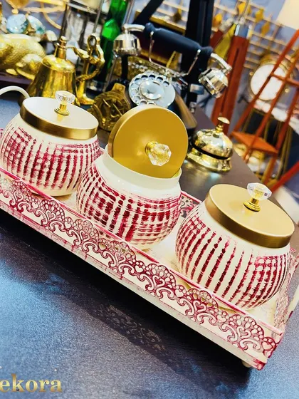 This set of three ceramic jars with a red and white striped pattern sits on an ornate metal tray. It's a vibrant and functional gift, perfect for storing dry fruits or sweets during festive celebrations.