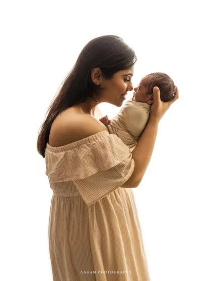 A new mother smiles down at her newborn baby. A beautiful and classic portrait that captures the pure joy and love of motherhood in a simple, bright setting.