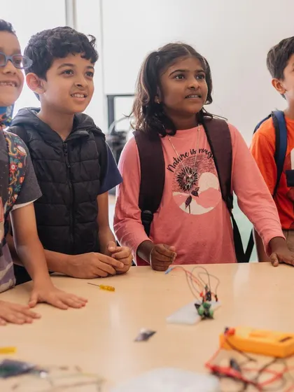 The moment of truth. A group of students watches in anticipation as their robotic creation comes to life, a shared experience of excitement and accomplishment.