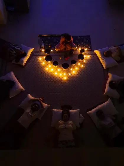 An overhead view of a group sound bath shows participants arranged in a circle, fostering a sense of community and shared peace. The singing bowls are placed centrally to ensure the sound envelops everyone equally.