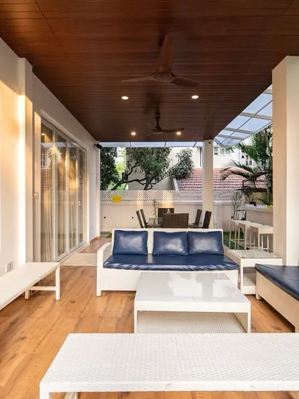 This covered villa patio gives off a coastal vibe, with white wicker furniture, deep navy cushions, and a natural wood ceiling creating a relaxed yet polished atmosphere.