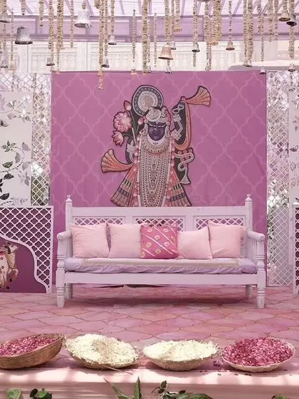 A unique seating backdrop featuring a large illustration of Shrinathji, blending traditional art with modern wedding decor for a Pichwai-themed event.