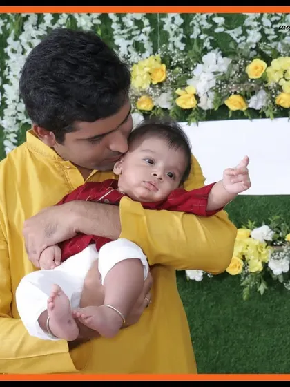 A father's gentle kiss on his newborn's head during a naming ceremony. This is the kind of heartfelt, candid moment we excel at capturing during family events.