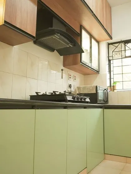 A different perspective of the renovated kitchen, showing the contrast between the wooden upper cabinets and the light green matte-finish lower cabinets. This two-tone approach adds depth and character to the space.