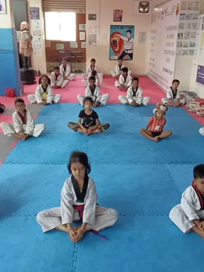 Students perform the butterfly stretch, an important exercise for hip flexibility essential for kicking.