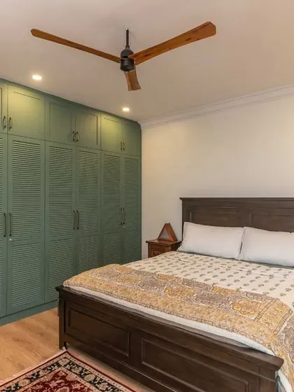 A wider view of the bedroom, showing how the large green wardrobe becomes the focal point of the room, complemented by a classic wooden bed.