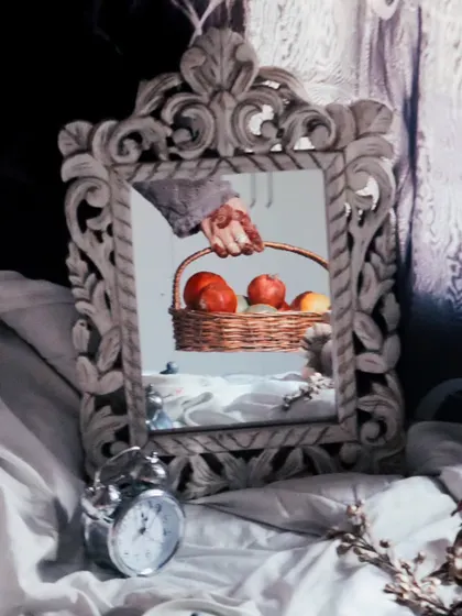 A creative and conceptual shot using a mirror to reflect a hand holding a fruit basket. This artistic approach adds a layer of depth and meaning to a simple still life.