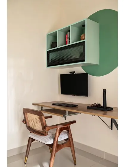 A detail of the study area, showing the floating desk, overhead storage, and the circular green paint feature that adds a graphic element.