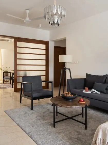 The informal family living space is designed to be calm and casual, with a comfortable grey sofa and a sliding screen to separate it from the dining area.