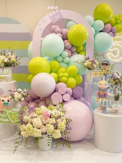 A beautiful pastel-colored balloon and floral arrangement. The soft colors and mix of textures create a dreamy and whimsical atmosphere, perfect for a first birthday or baby shower.