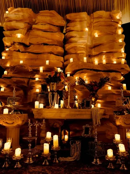 Inside the grotto-styled cave, a fireplace-like structure is filled with candles, creating a warm and enchanting glow against the rock-textured walls.