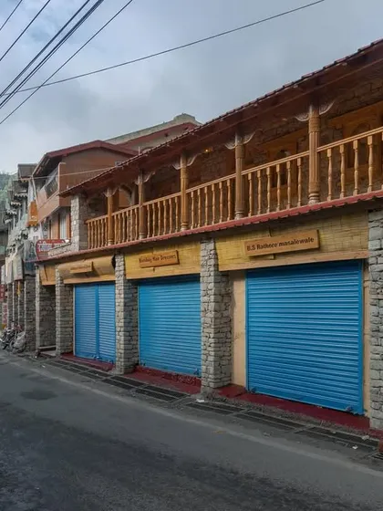 The restored facade along the street, with its new wooden signages, stone finials, and bright blue shutters, brings a renewed sense of order and charm.