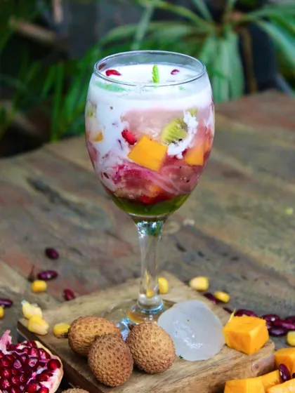 Our refreshing Ice Kachang, beautifully layered in a glass with tropical fruits like lychee, mango, and pomegranate.