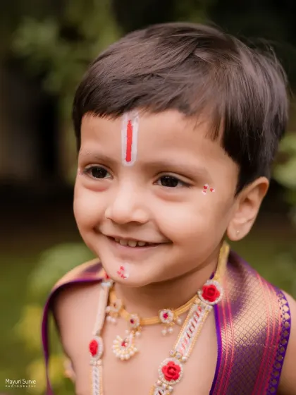 A close-up shot capturing the sweet, innocent smile of this little boy during his Krishna-themed session. The details, like the tilak and gentle expression, are what make these portraits so precious.