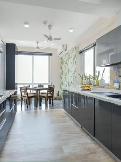 This open-style parallel kitchen flows directly into the dining area, making it ideal for entertaining. The high-gloss grey cabinets and colorful tile backsplash add a touch of modern elegance.