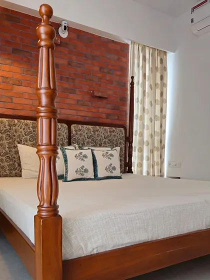 A classic four-poster bed against an exposed brick wall, creating a perfect blend of rustic charm and timeless elegance.