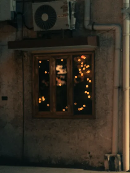 A quiet moment on Diwali night. The festive lights inside a home, seen through a window, create a warm, cozy, and slightly mysterious bokeh photograph.