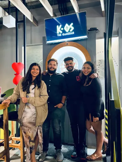 A group of friends posing for a picture after a fun-filled night of games. The dartboard area is a great spot to capture memories.