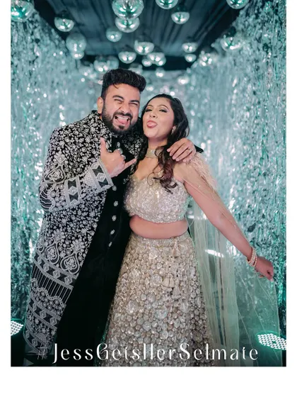 A fun, candid moment of the couple posing in a futuristic, silver-tasseled tunnel photo booth.