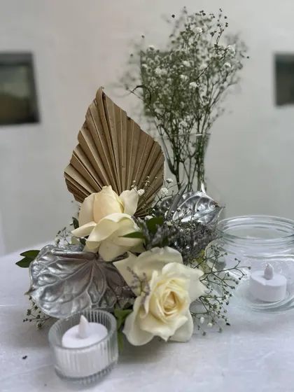 A simple yet elegant table centerpiece for the cocktail party, with white roses, dried palms, and baby's breath, creating a cohesive look throughout the event space.
